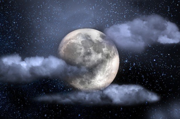 Large moon with clouds in starry night sky.