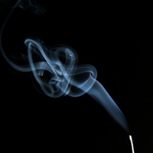 Nicotine smoke rings rising from cigarette against black background