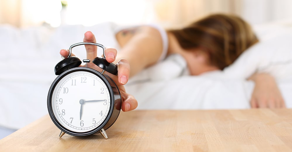 Woman reaching for an alarm clock