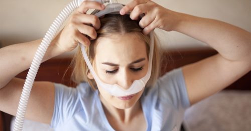 Woman putting on CPAP equipment