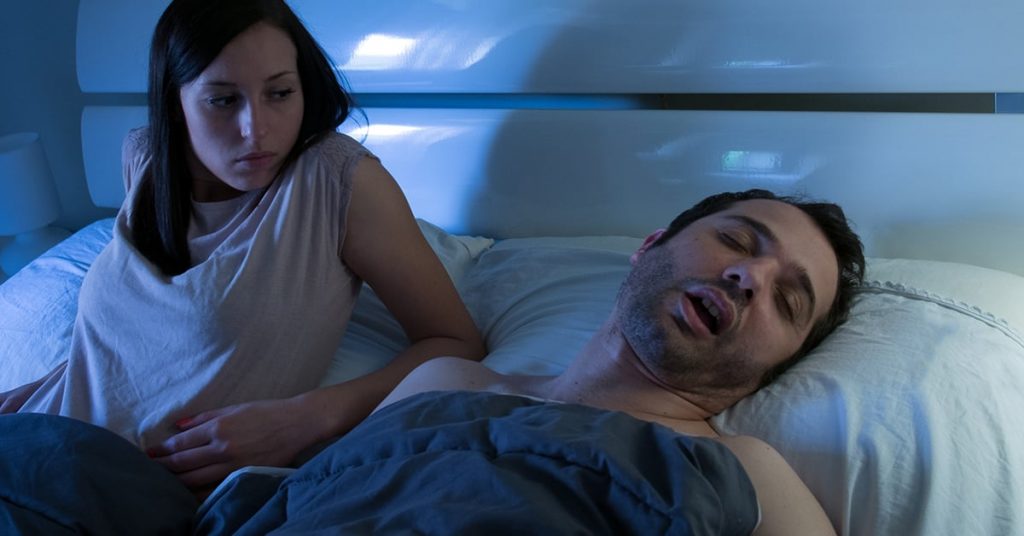 Man Snoring while wife looks concerned.